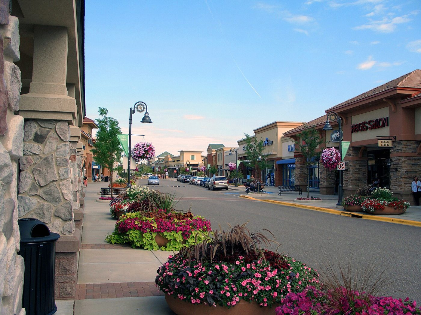 Flower-lined sidewalk and shops at the west end of Arbor Lakes