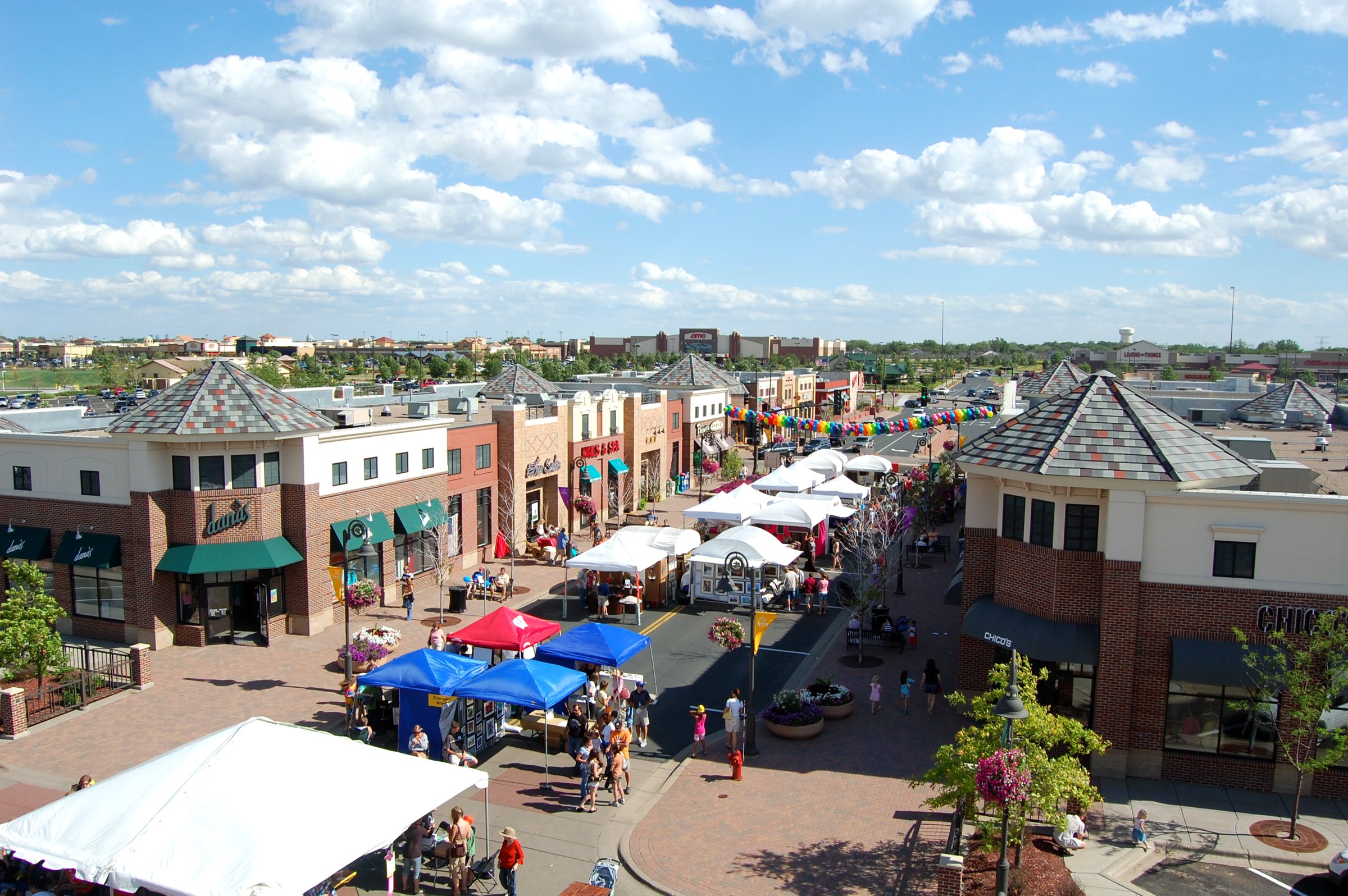 Main Street in Maple Grove on a sunny day with tents and shoppers